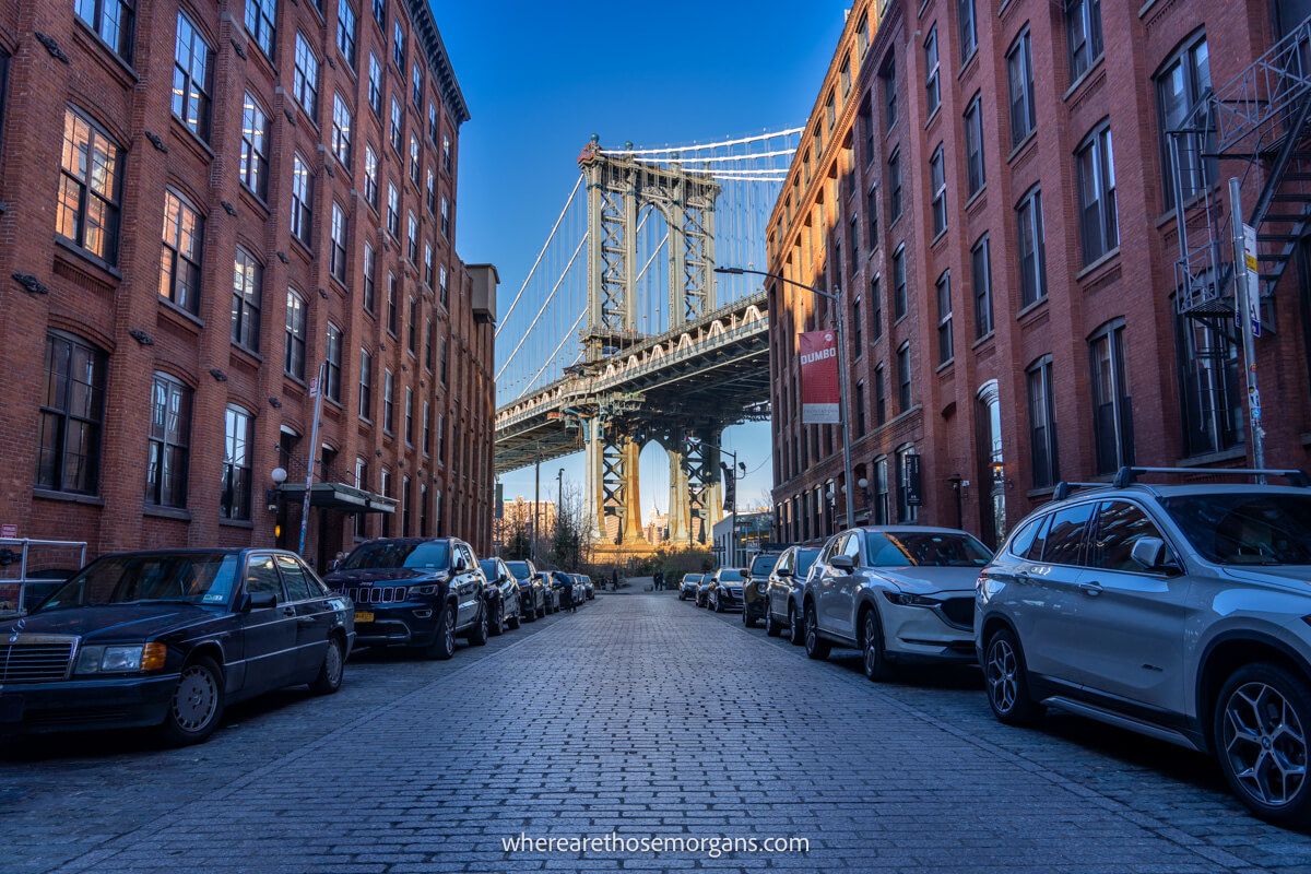 Street in Brooklyn with cars parked next to buildings leading to the Manhattan Bridge from Dumbo