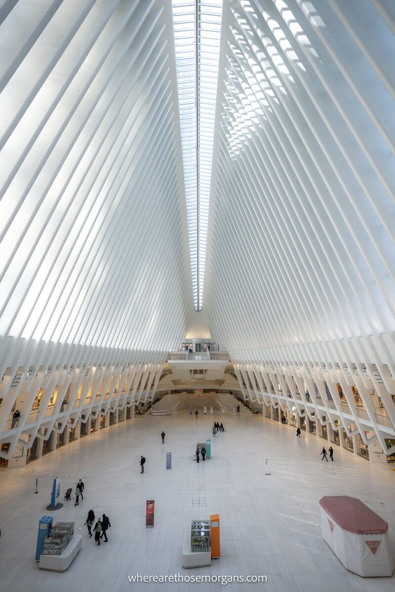 Large cavernous building interior with a white floor leading up to tall white metal beams joining in the middle high above
