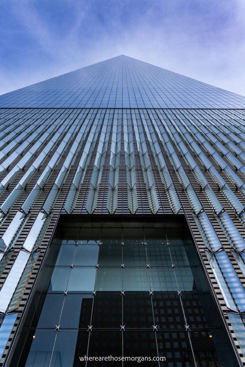 Looking up at a towering glass skyscraper from below as it bursts into a blue sky