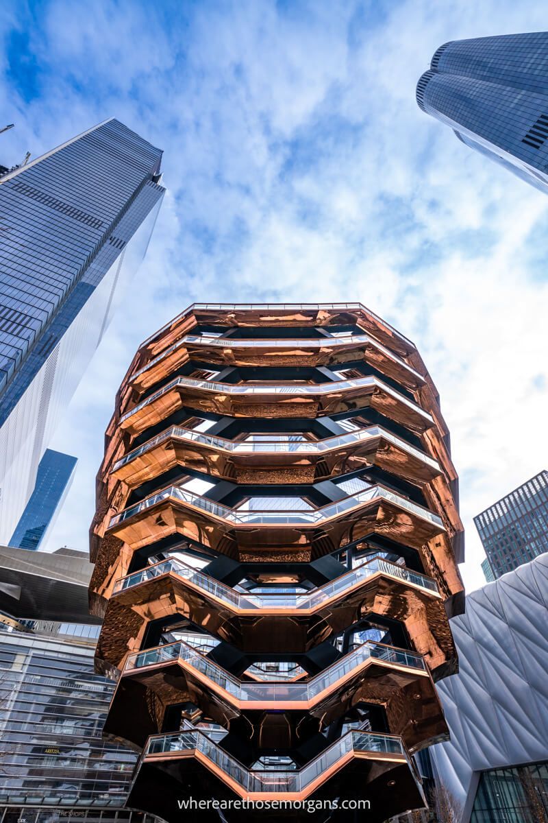 Vessel in New York City large orange copper colored structure surrounded by tall skyscrapers with light clouds in the sky
