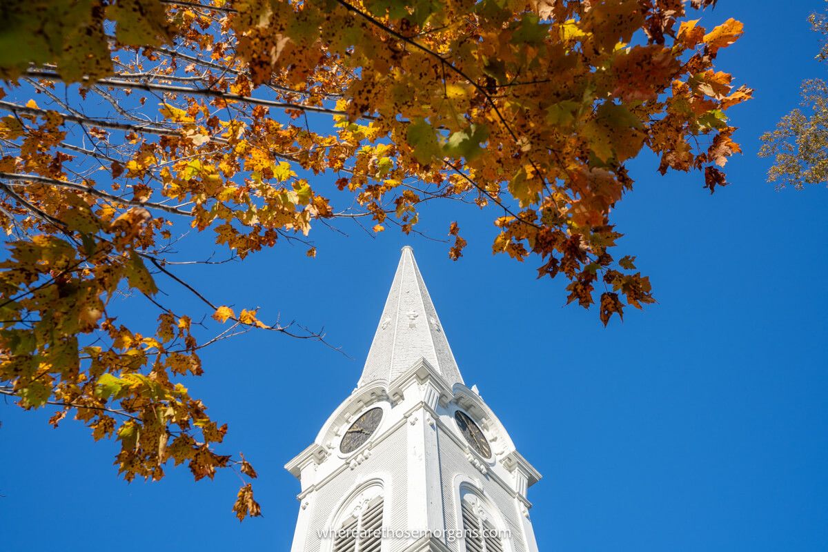 A white church spire with bright orange leaves