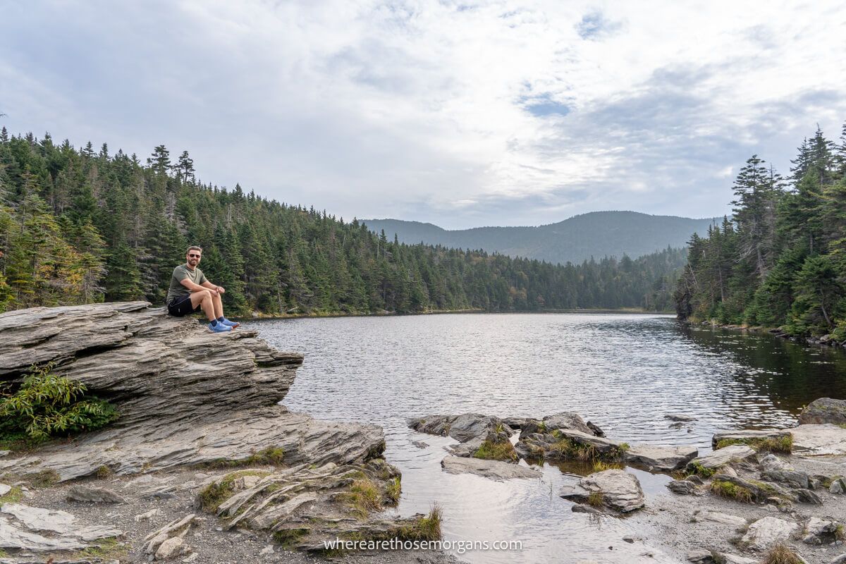 Hiker sitting on a large rock at Sterling Pond in Stowe, Vermont