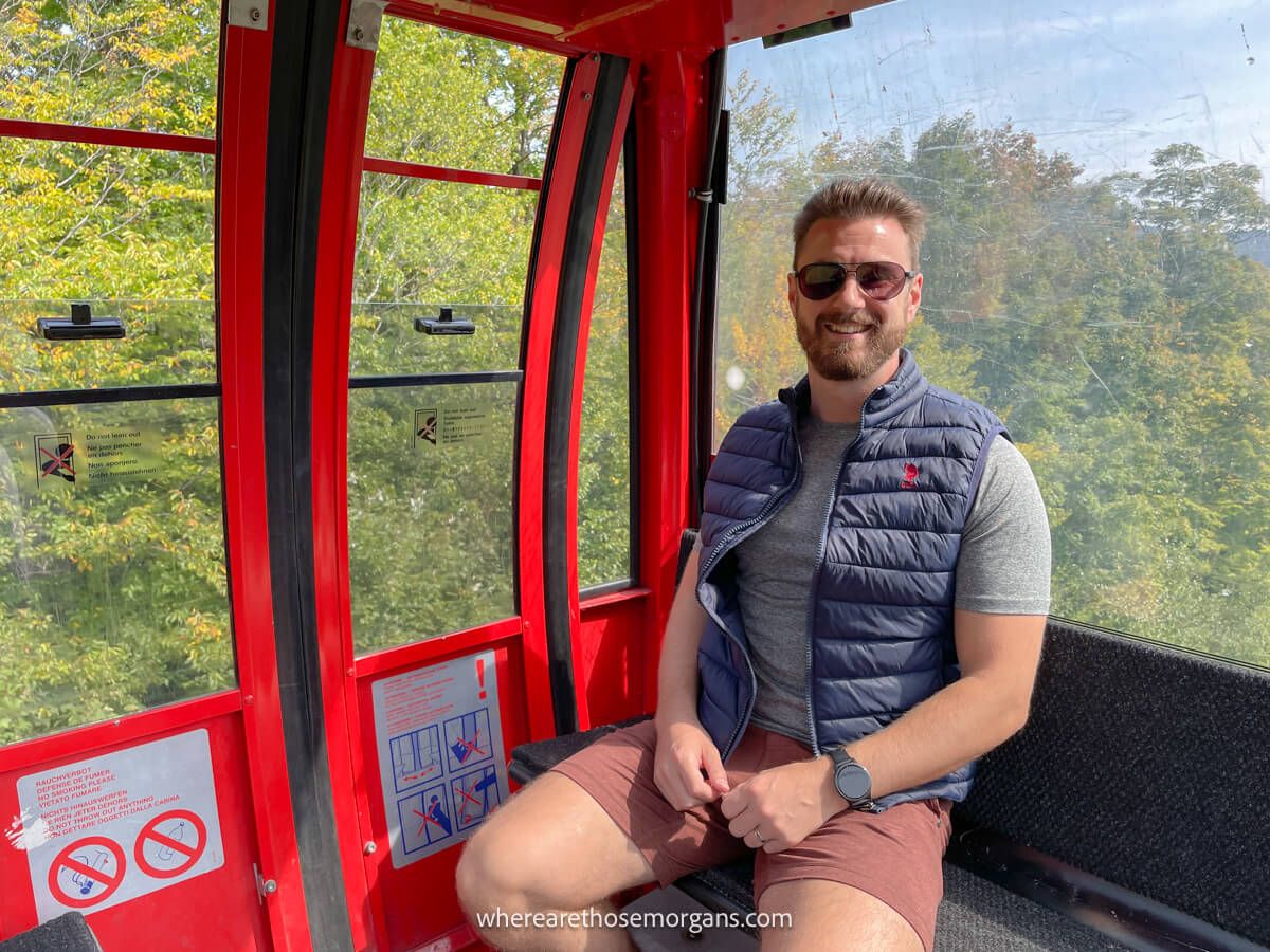 Man sitting in a car of the Stowe Gondola as it climbs up Mount Mansfield