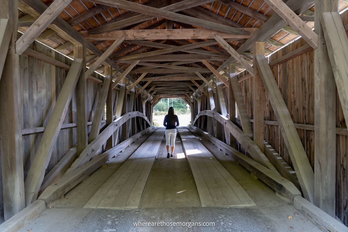 Woman walking across the long wooden covered bridge in vermont