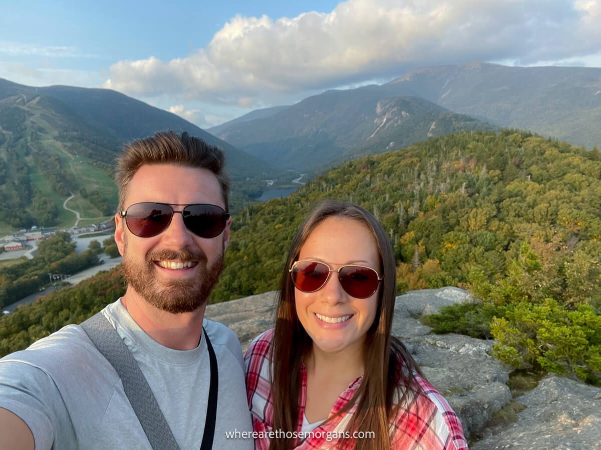 Couple with sunglasses on taking a selfie at sunset from a mountain summit in New Hampshire