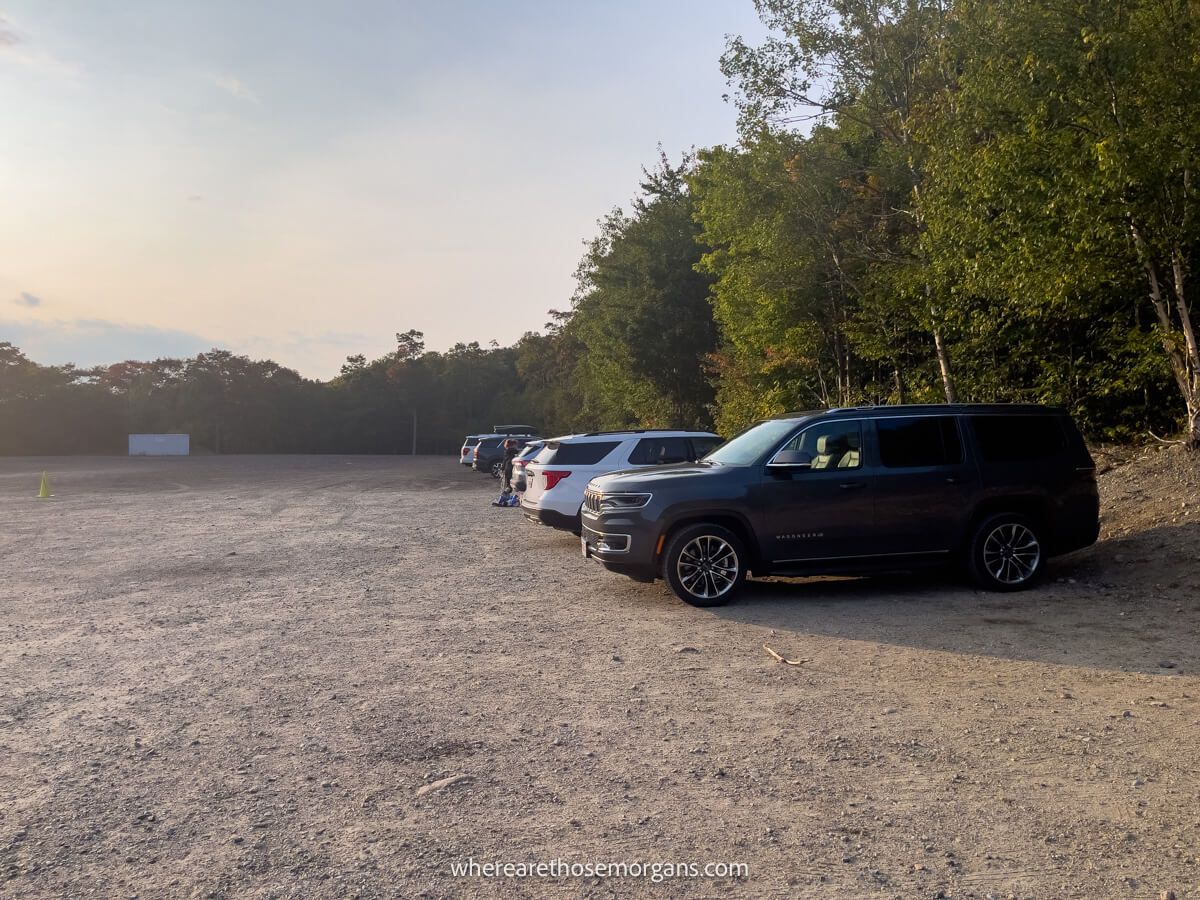 Large gravel parking lot with a few cars parked close to sunset with soft light