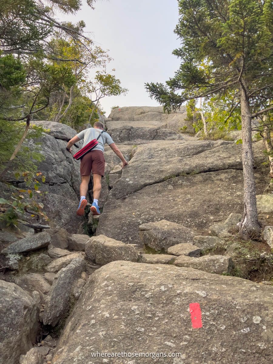 Hiker climbing up a slick rock trail to reach a mountain summit
