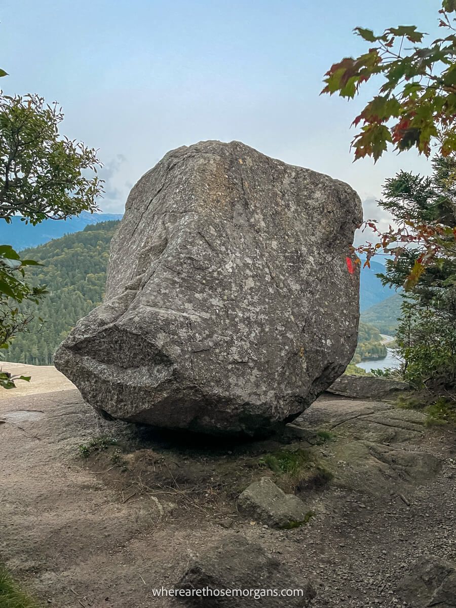 Huge lone boulder perched on a flat rocky surface with distant views behind the boulder