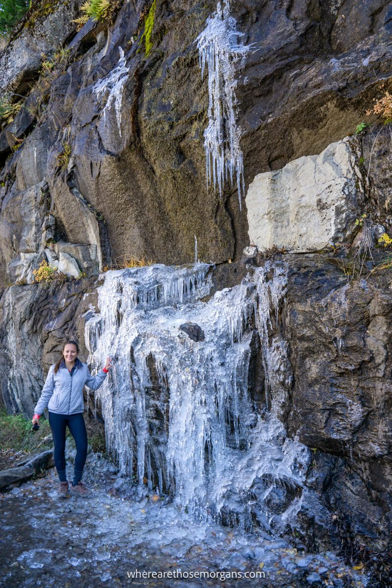 Hiker pointing to a large patch of ice on a hiking trail and rocky wall
