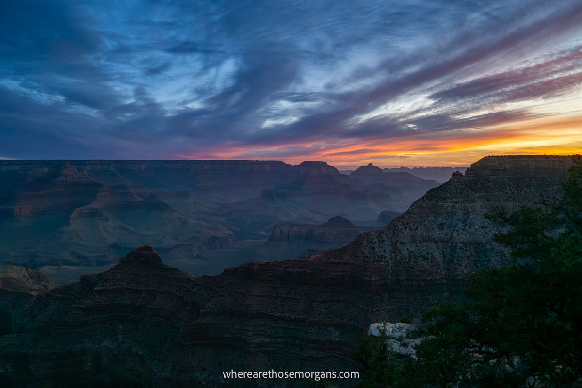 Wide open and far reaching view into Grand Canyon South Rim from near Mather Point at sunrise with colorful clouds and deep dark shadows inside the canyon