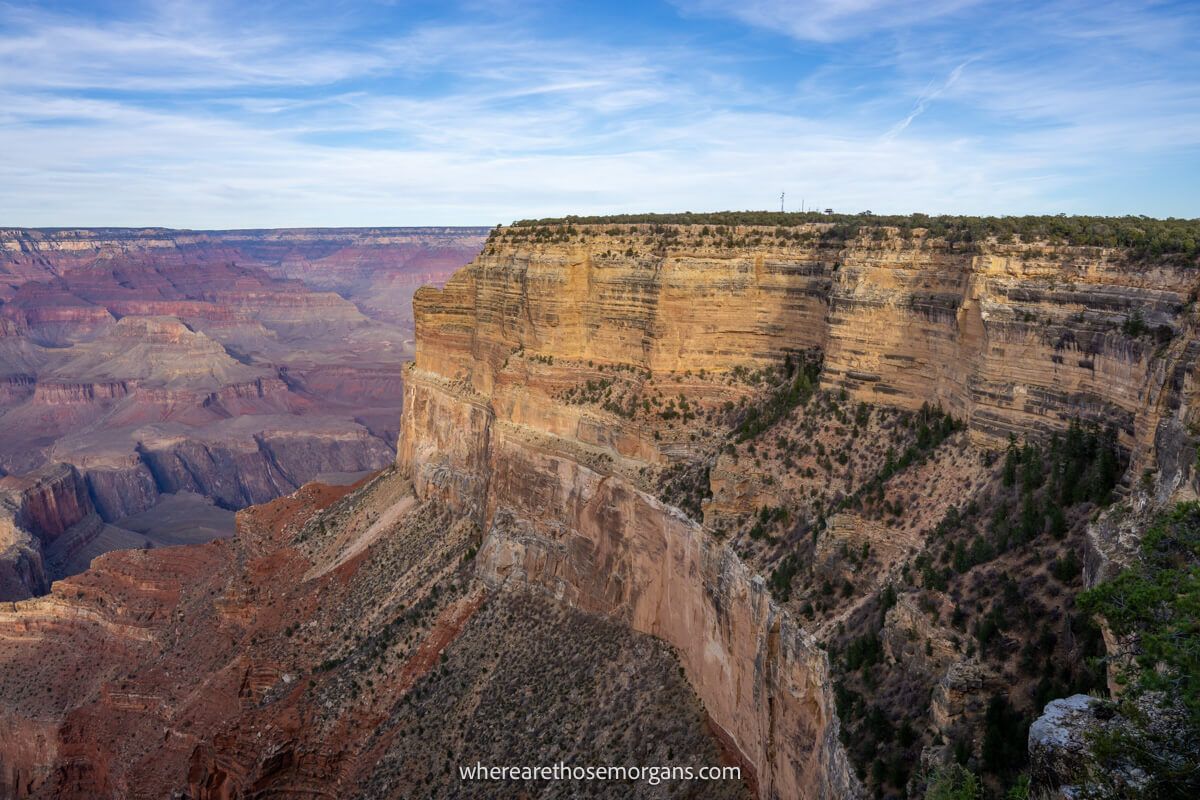 Large curving rocky outcrop at the top of a deep and vast eroded rocky landscape with light clouds above