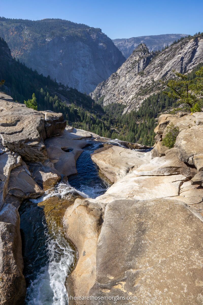 Photo of a thin waterfall dropping over a cliff with far reaching views of granite rock formations from Nevada Falls on the Mist Trail hike in Yosemite