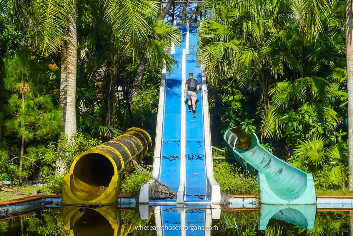 Man walking up the right side of a blue waterside in an abandoned waterpark