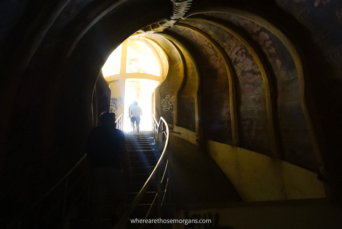 Two people walking up the stairs inside an old aquarium in the dark
