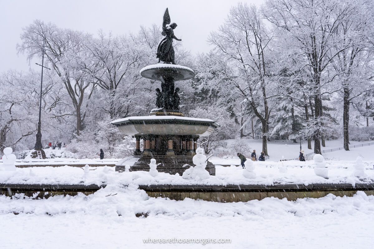 Photo of Bethesda Fountain in Central Park covered in snow with small snowmen on its perimeter wall in winter