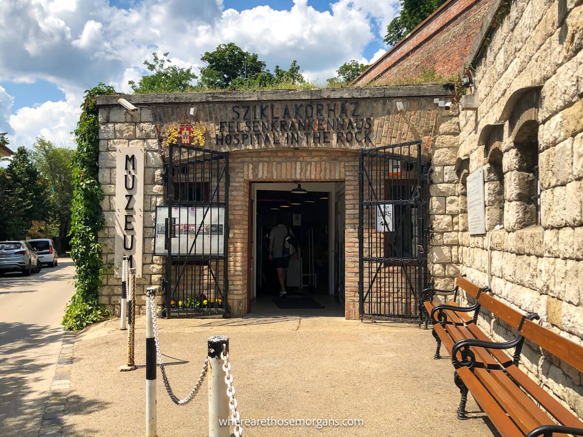 The entrance to an attraction in Budapest through a door into a stone building that leads underground