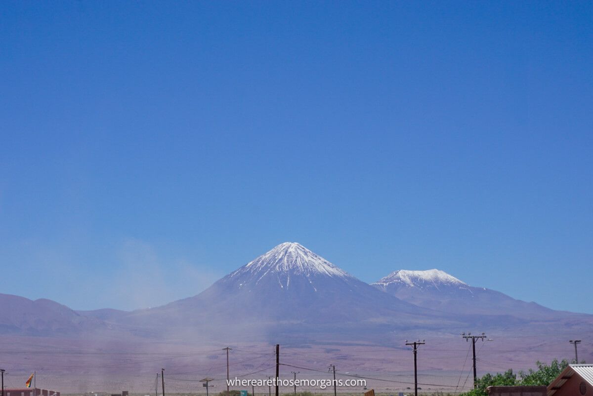 Two tall snow capped volcanoes underneath a brilliant blue sky near San Pedro de Atacama in Chile