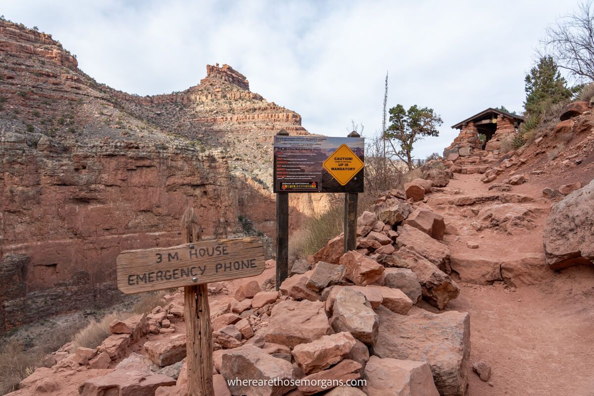 Photo of wooden signs in large red stones on a dirt trail inside a red rock canyon