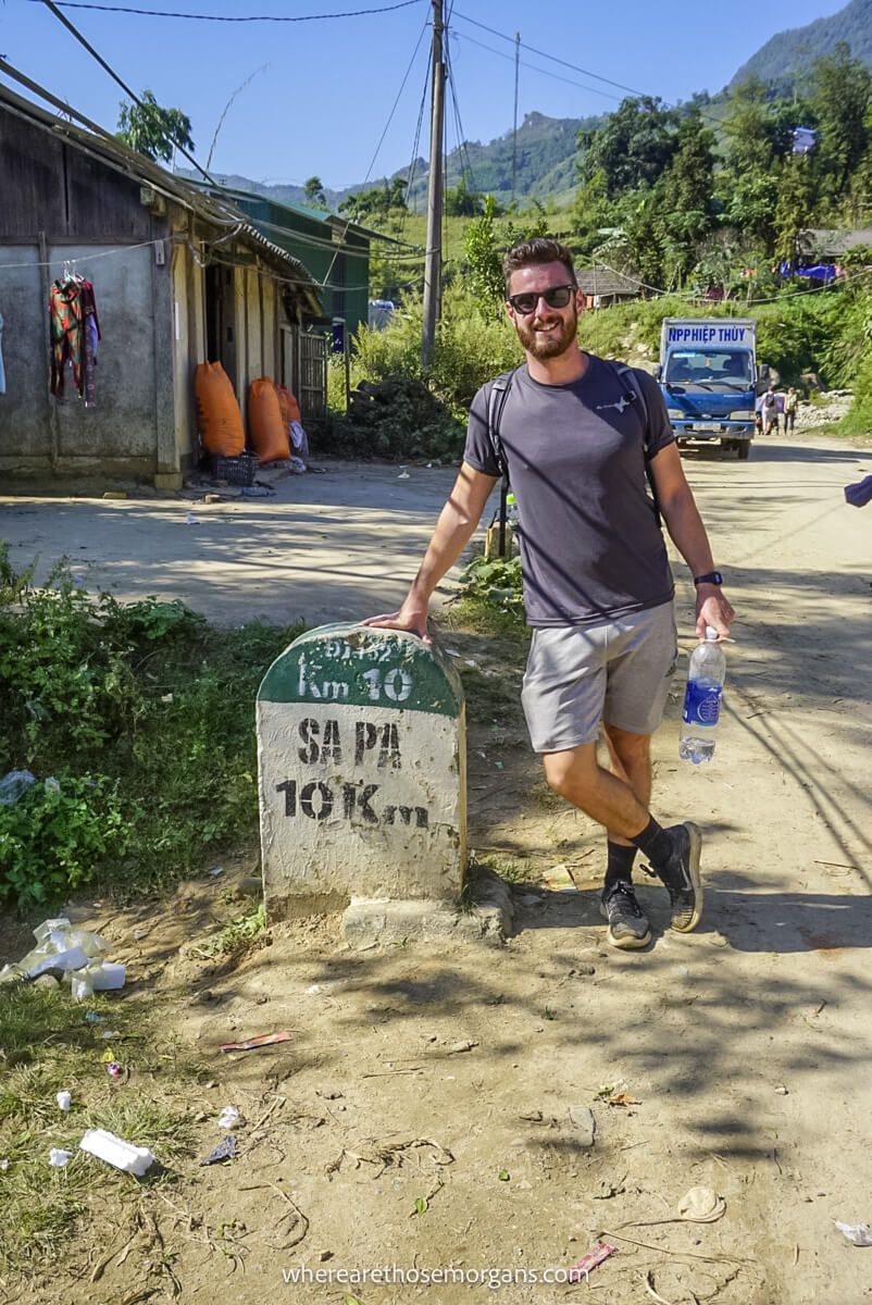 Man resting against a mile marker for Sapa, Vietnam