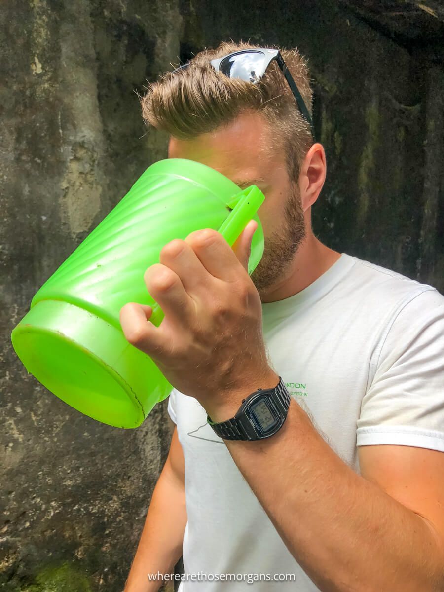 Man taking a sip of happy water from a green bucket