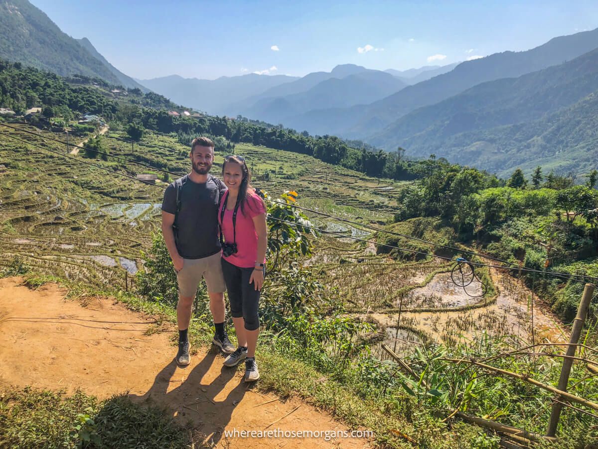 Two tourists posing for a photo with the mountains of Sapa in the background