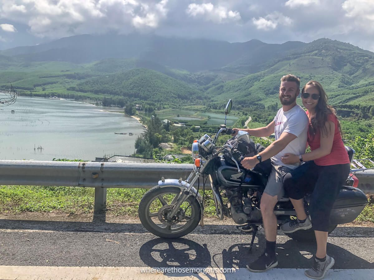 Man and woman sitting on a motorbike along a road in Vietnam