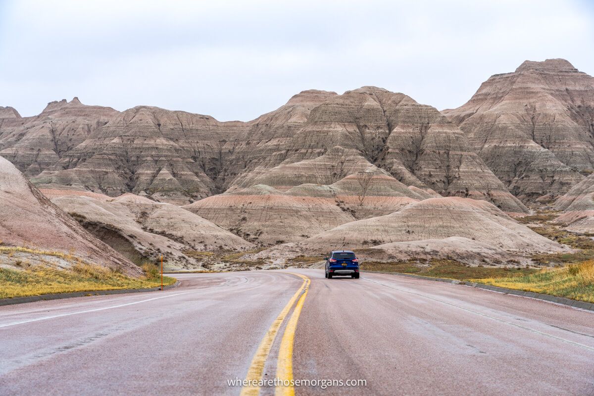 Blue SUV with hills from the Badlands in the background during a road trip