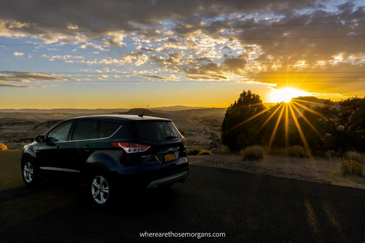 A blue ford SUV with the sun setting in the background during a road trip in Utah