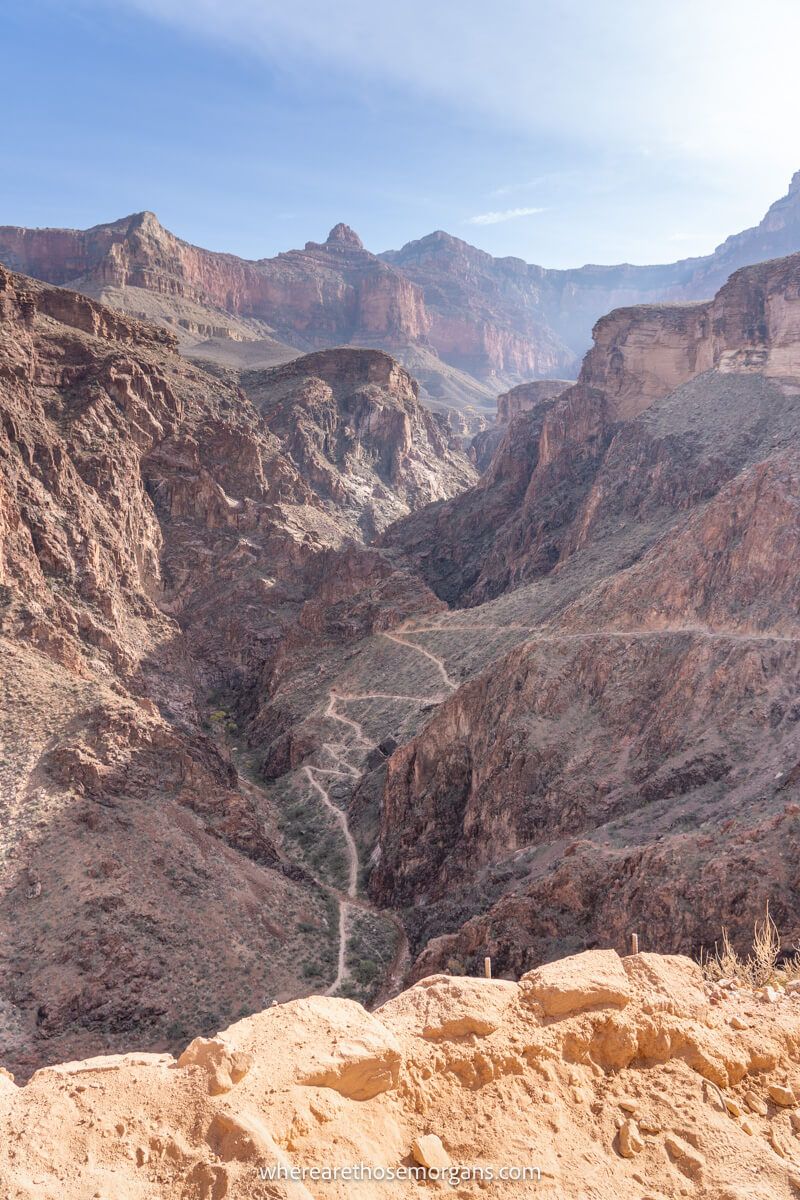 Photo of a wide open red rock canyon with a hiking trail zig-zagging down the canyon via switchbacks