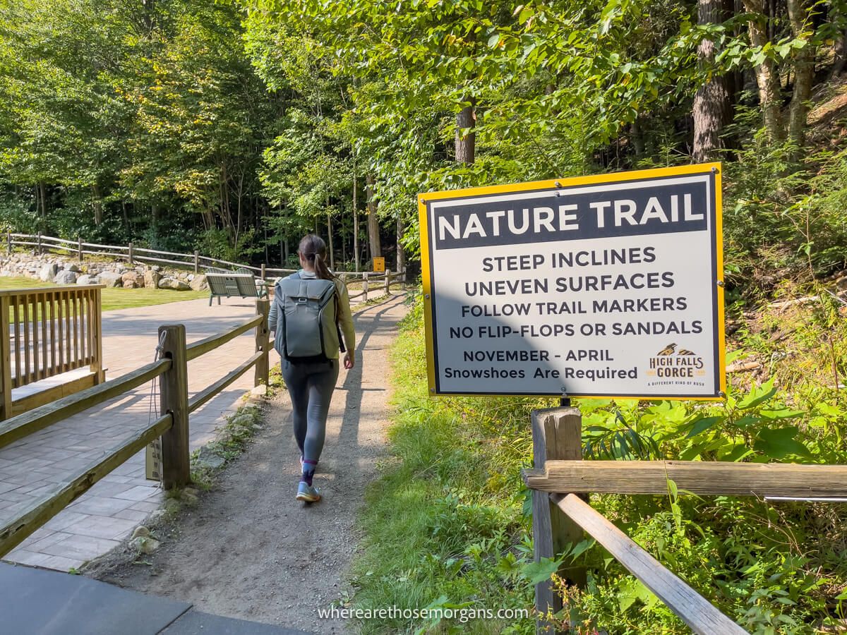 Photo of a hiker entering a nature trail with a sign stating rules for the hike