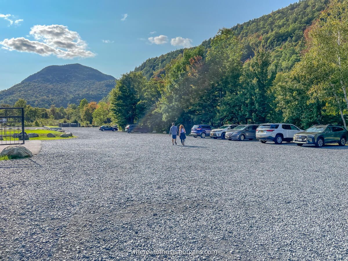 Photo of a large gravel parking area next to trees and a distant mountain under a clear blue sky at High Falls Gorge in Upstate NY