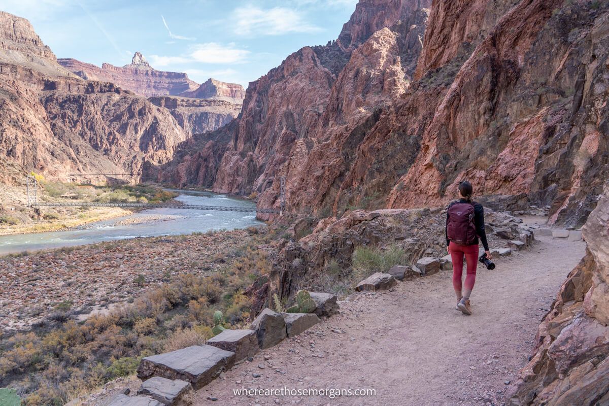 Photo of a hiker walking on Bright Angel Trail next to the Colorado River at the bottom of the Grand Canyon