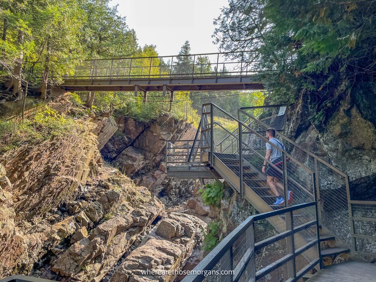Hiker walking up a metal staircase connected to a cliff wall inside a ravine