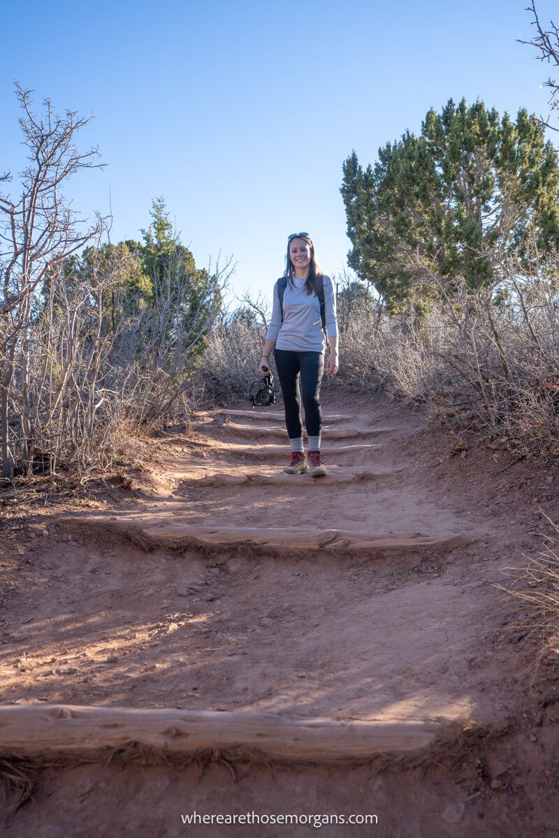 Photo of a hiker on a dirt packed walking path next to desert vegetation holding a camera on a gimbal