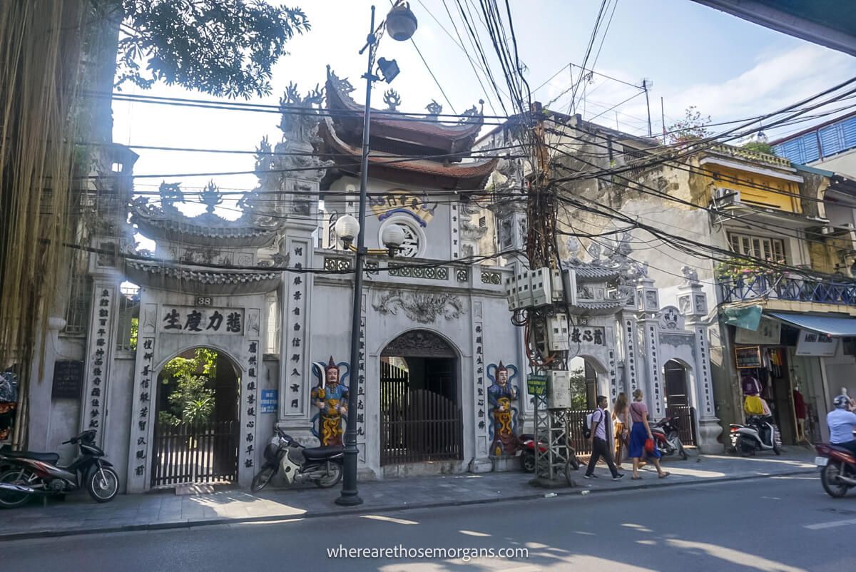 An old white gate in Vietnam with a large electric pile on nearby