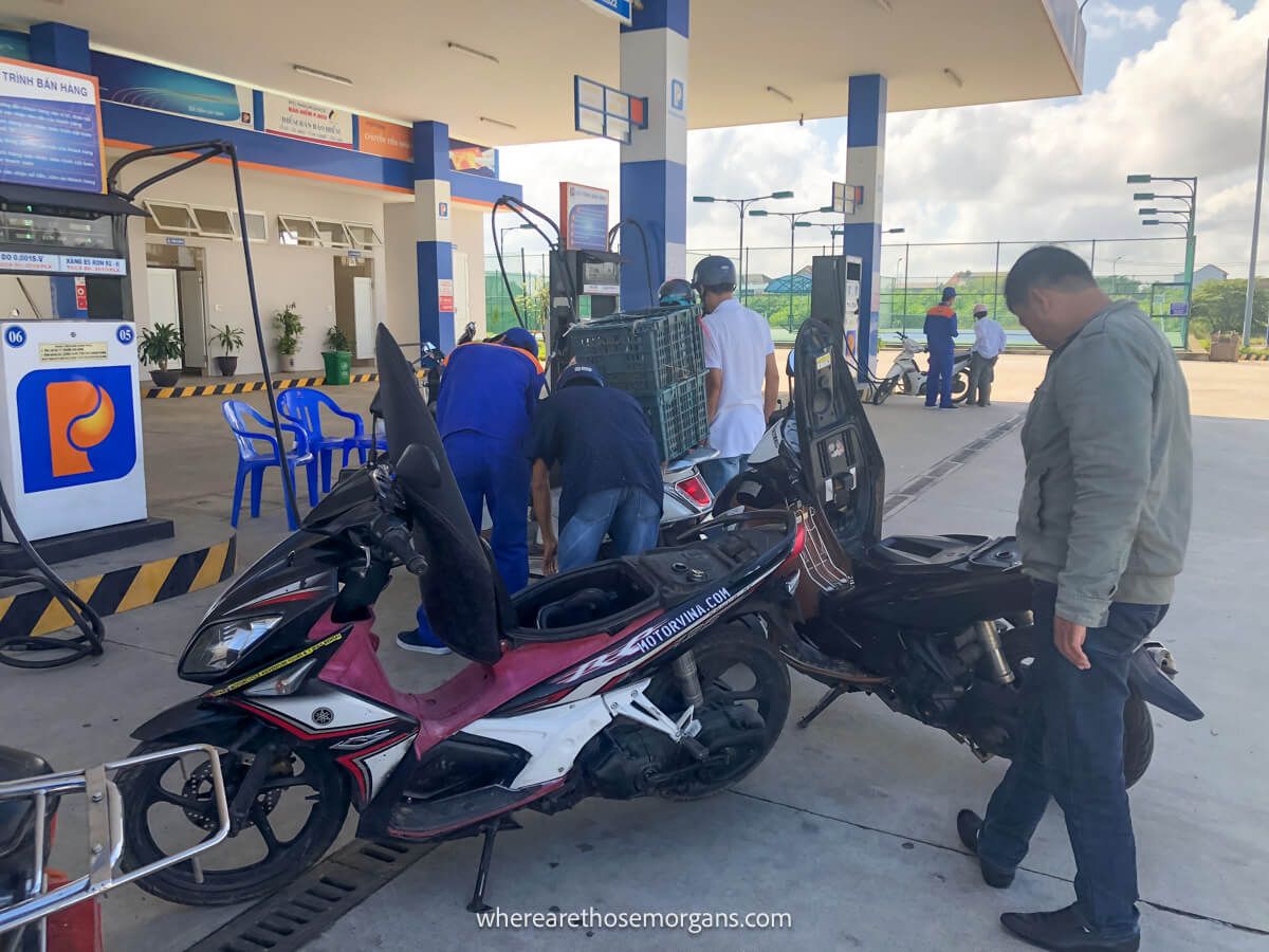 Tour guide putting gas into two motorbikes