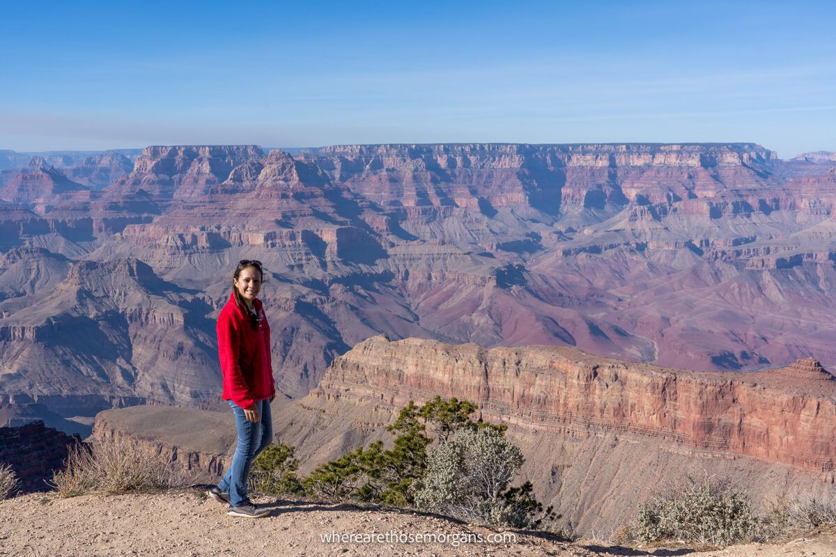 Photo of a tourist in red fleece standing at a viewpoint in Arizona with far reaching views over red rock formations