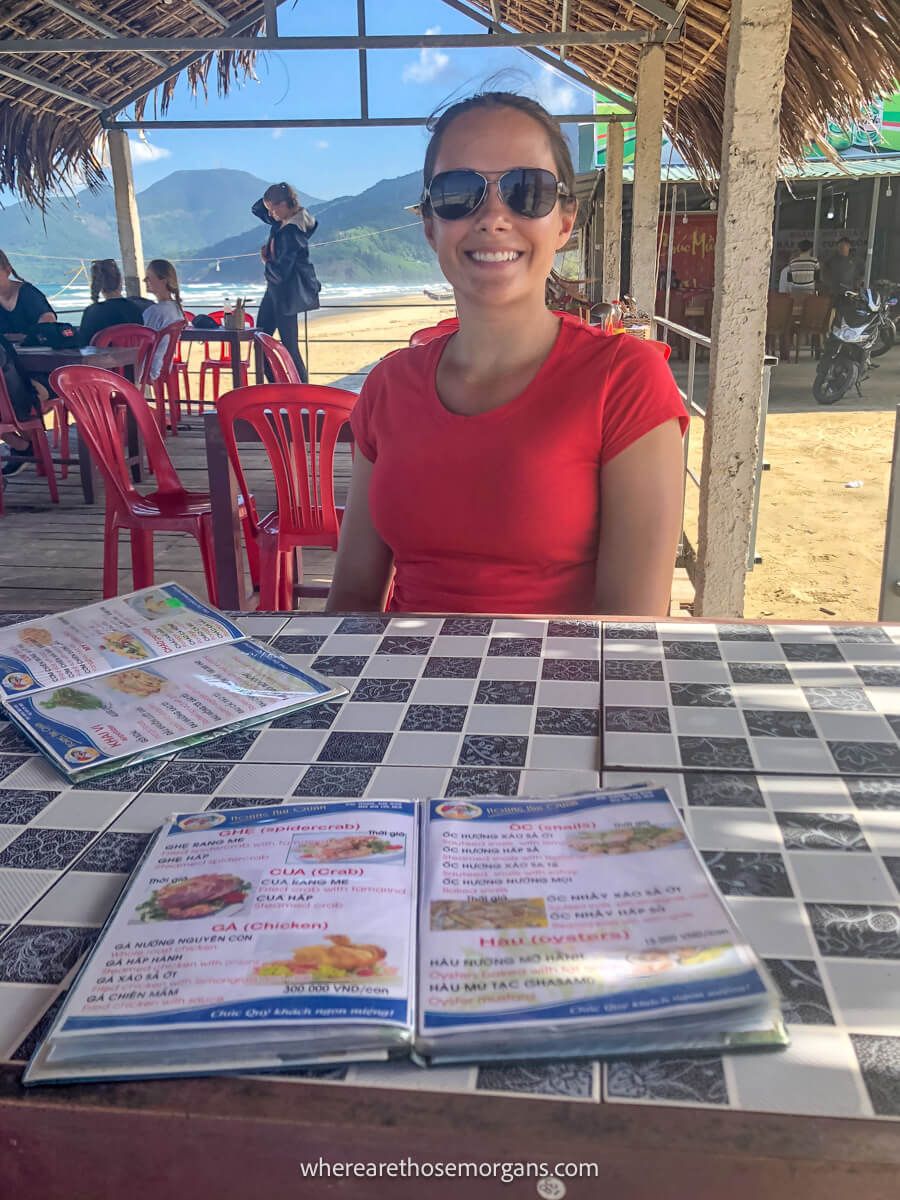 Woman sitting at a beachside restaurant with two menus on the table