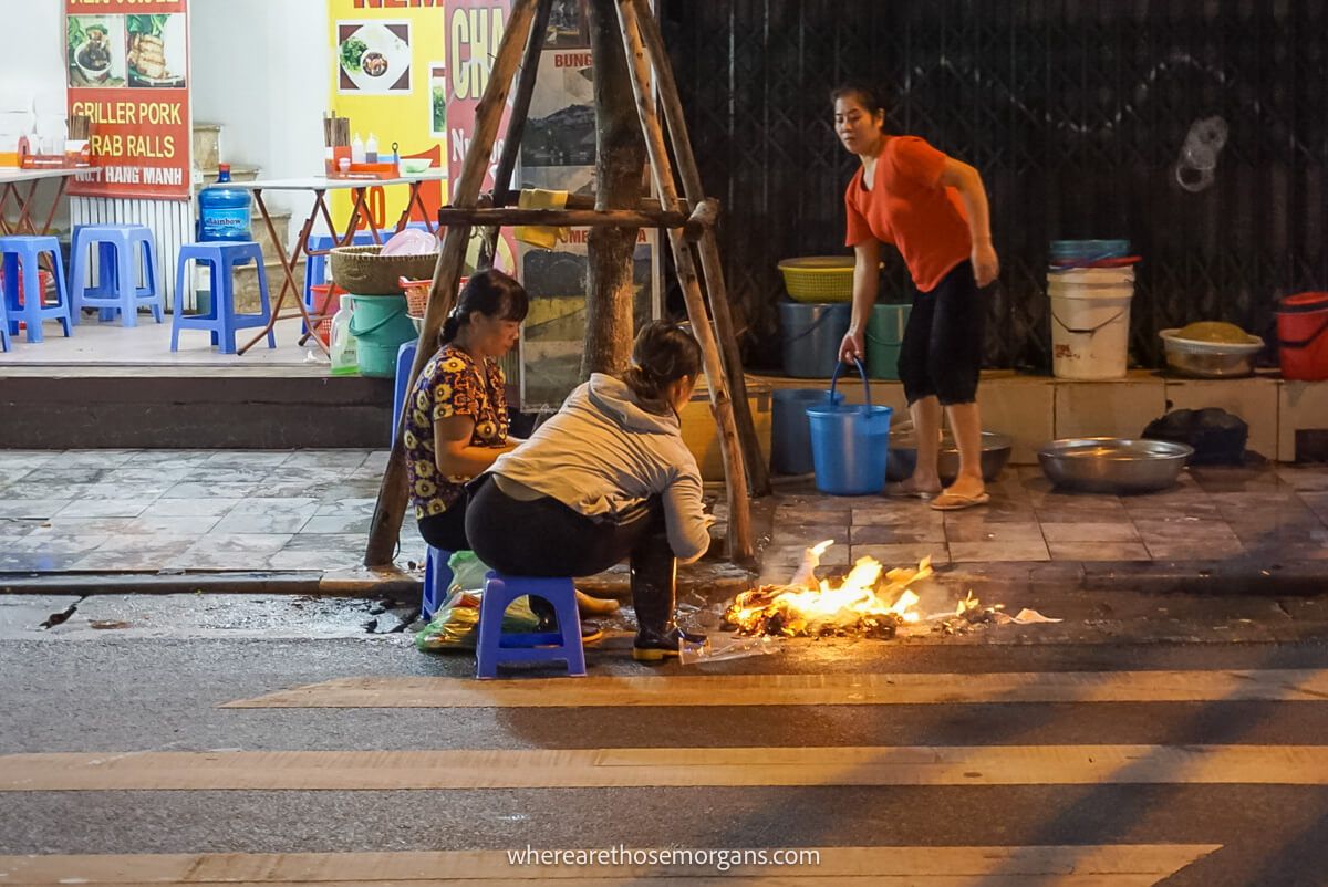 Three women tending to a fire in the streets in Hanoi, Vietnam