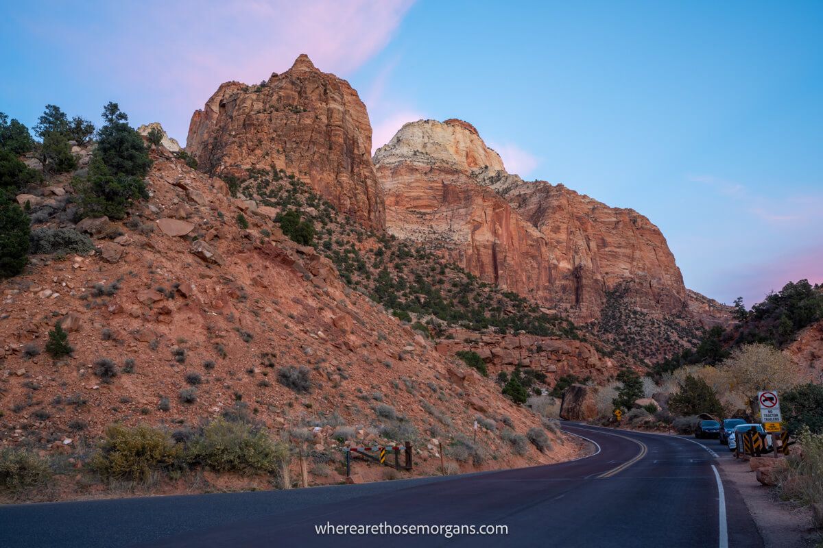 Photo of red rock cliffs next to a road running through Zion at sunset