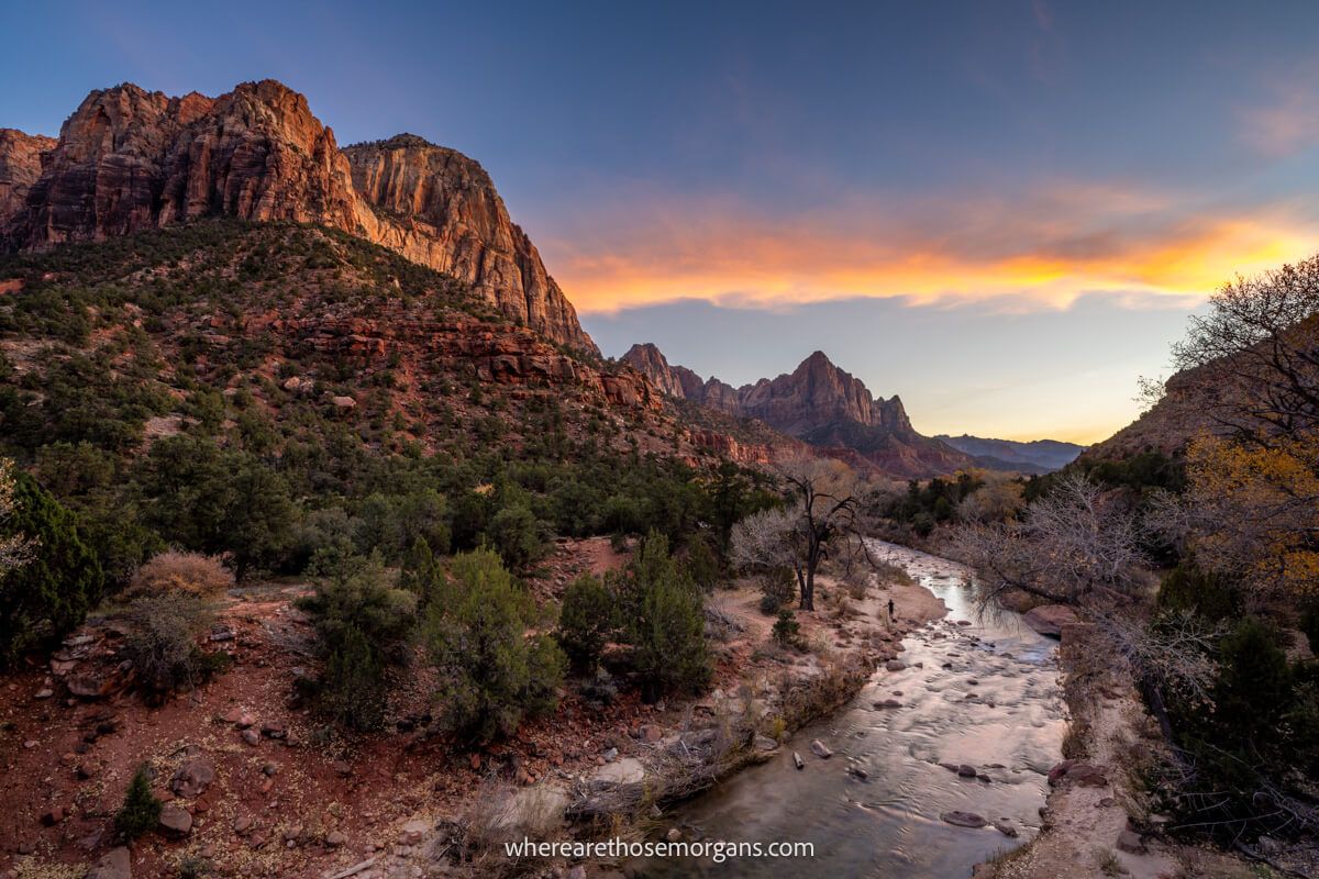 Photo of a river running through Zion National Park next to towering red rock cliffs at sunset