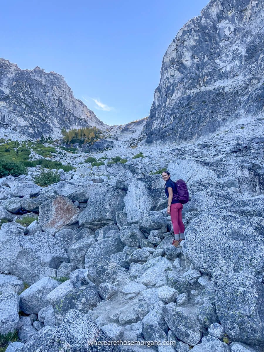 Photo of Kristen Morgan climbing a steep boulder trail up a mountain pass on The Enchantments hike