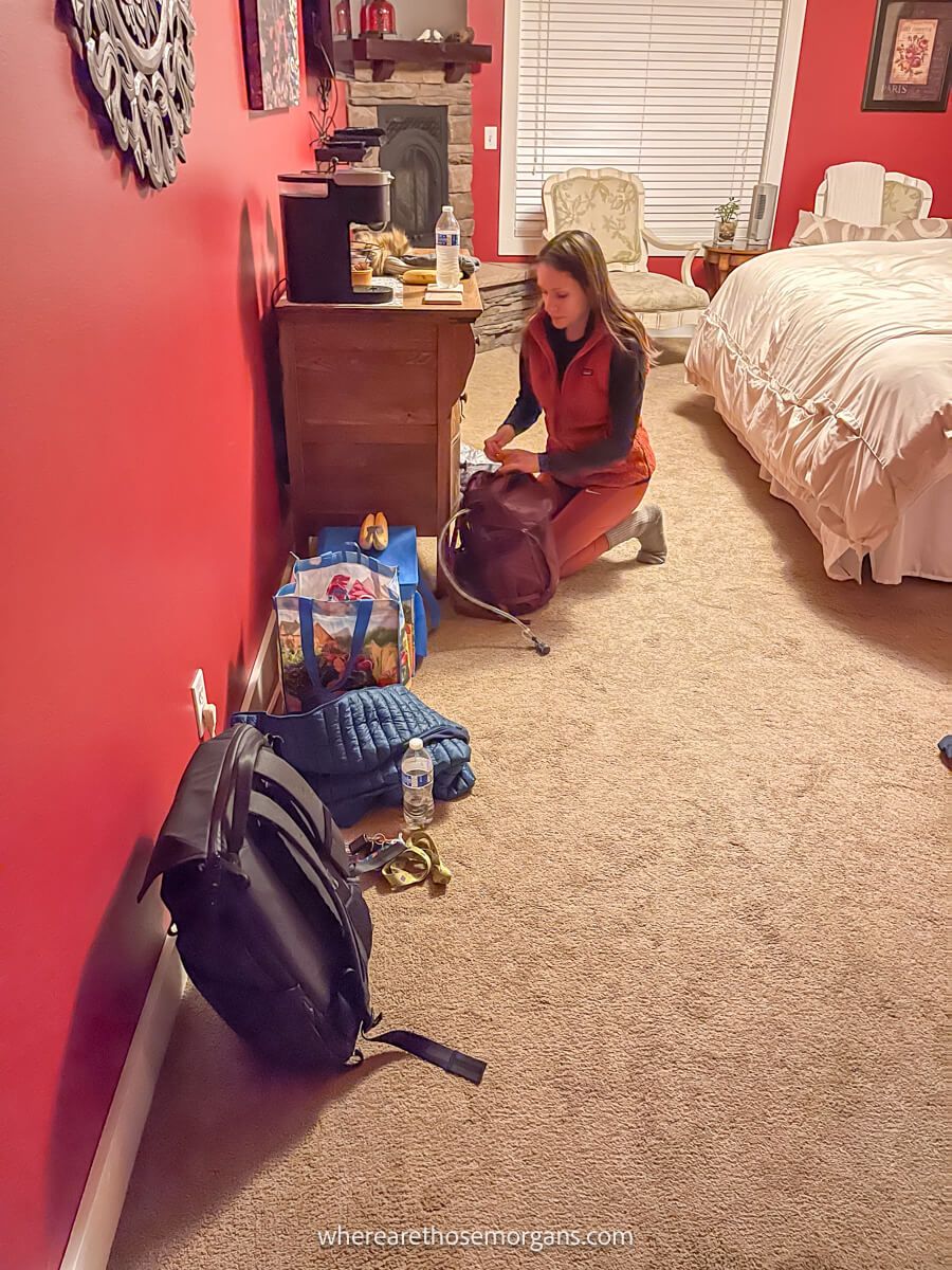 Photo of a person packing food and clothes into a backpack inside a hotel room