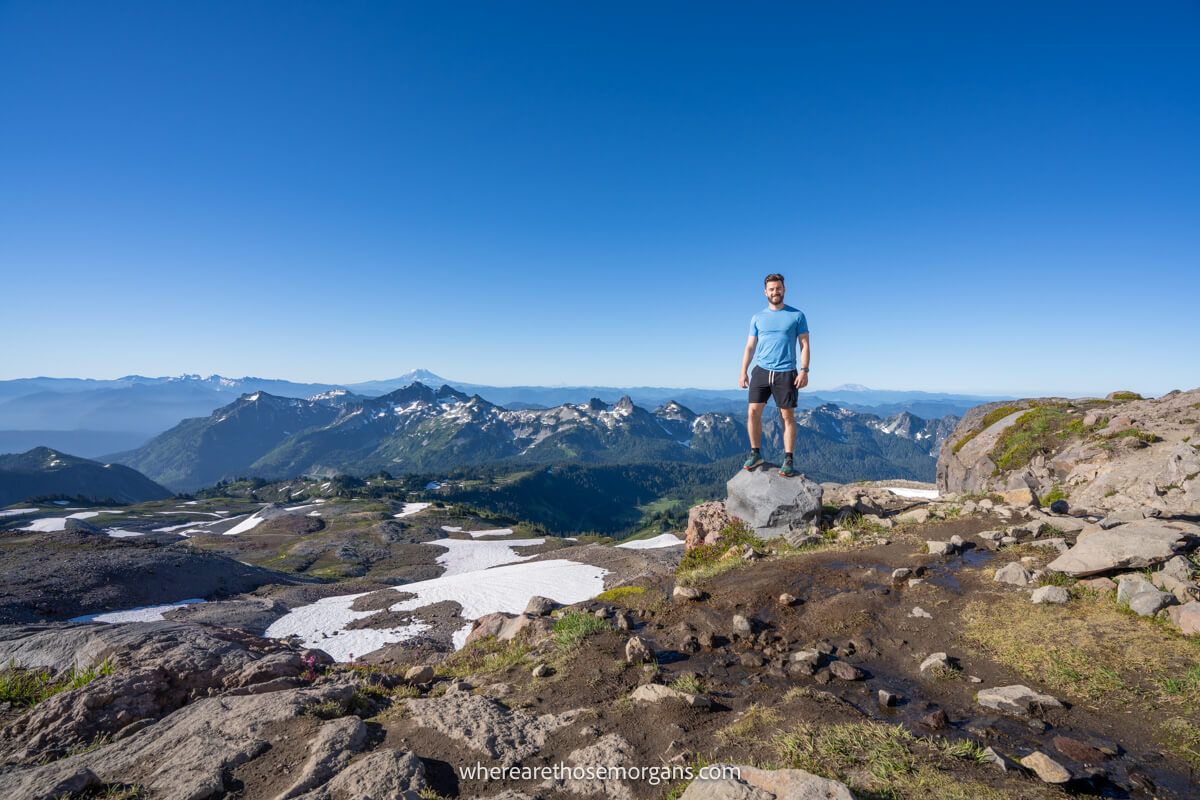 Photo of Mark Morgan from Where Are Those Morgans standing on a rock at the summit of Skyline Trail in Mt Rainier on a sunny and clear day under a blue sky with far reaching views