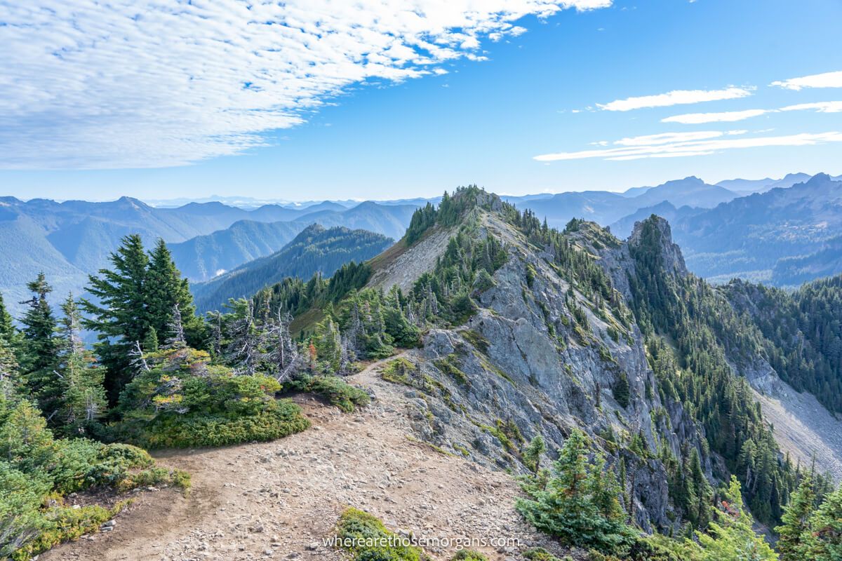 Photo of a hiking path leading to a jagged narrow rocky ridge line summit at the top of a mountain range