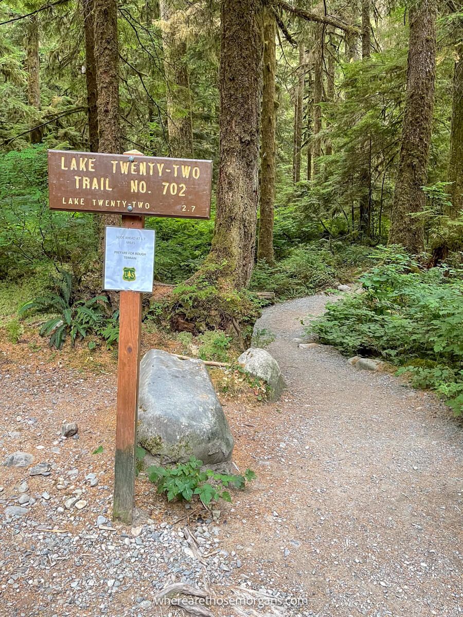 Photo of Lake Twenty-Two Trailhead wooden hiking sign next to a path leading into a forest