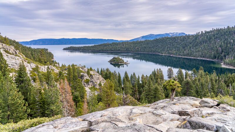 Photo of a lake with rolling hills covered in trees under a cloudy sky in Lake Tahoe