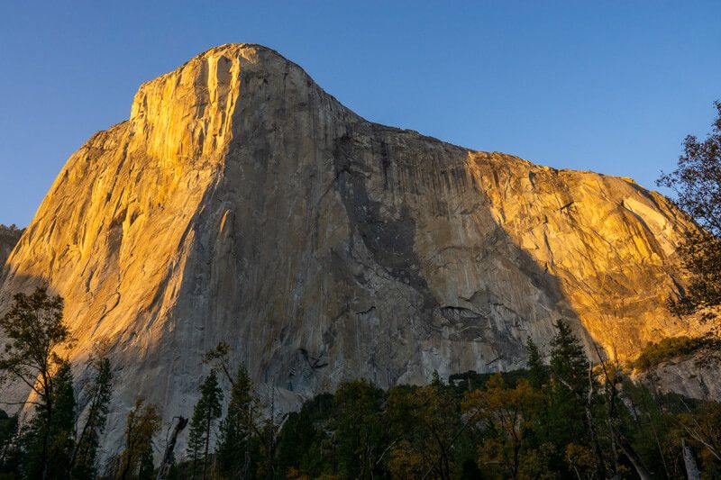 Photo of a massive granite rock formation half covered in sun and half in shadow on a clear day in Yosemite National Park