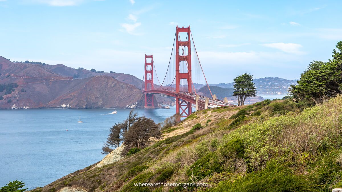 The Golden Gate Bridge from a grassy hillside on a slight angle at a fair distance so the bridge appears small