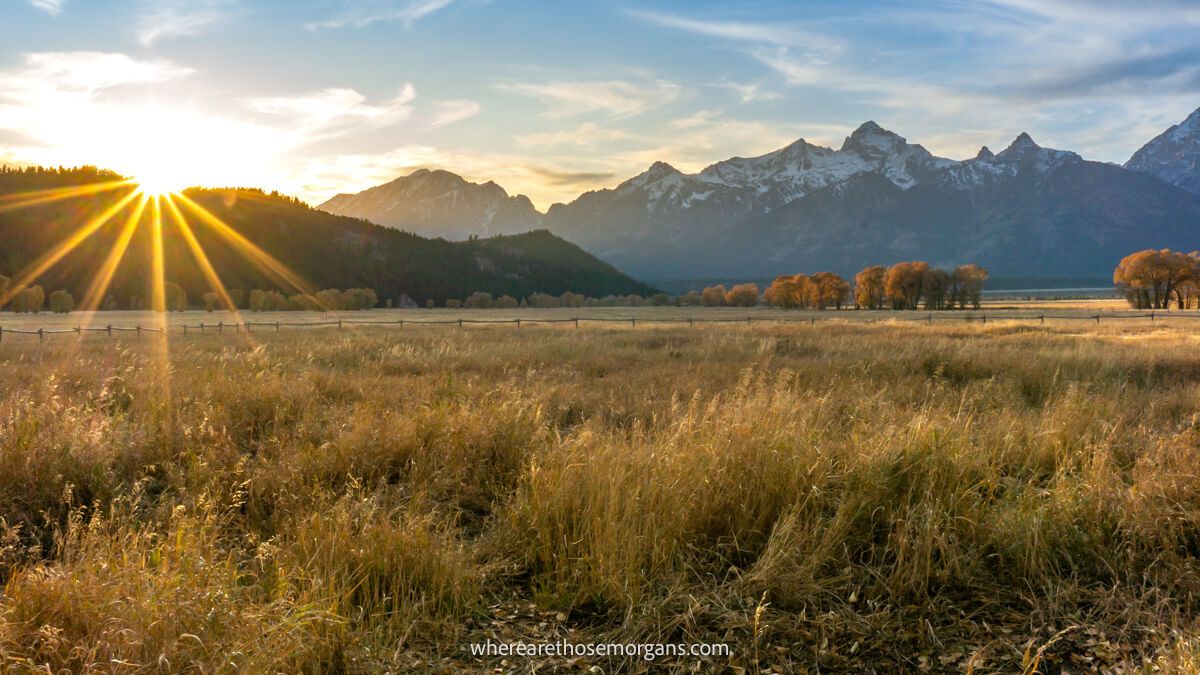 Photo of a sunset over a wide open grassy plain with mountains in a distant haze